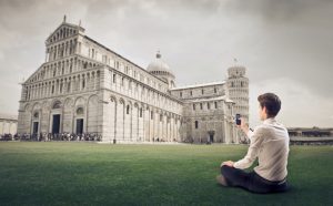 a man sitting on the ground in front of a large building.